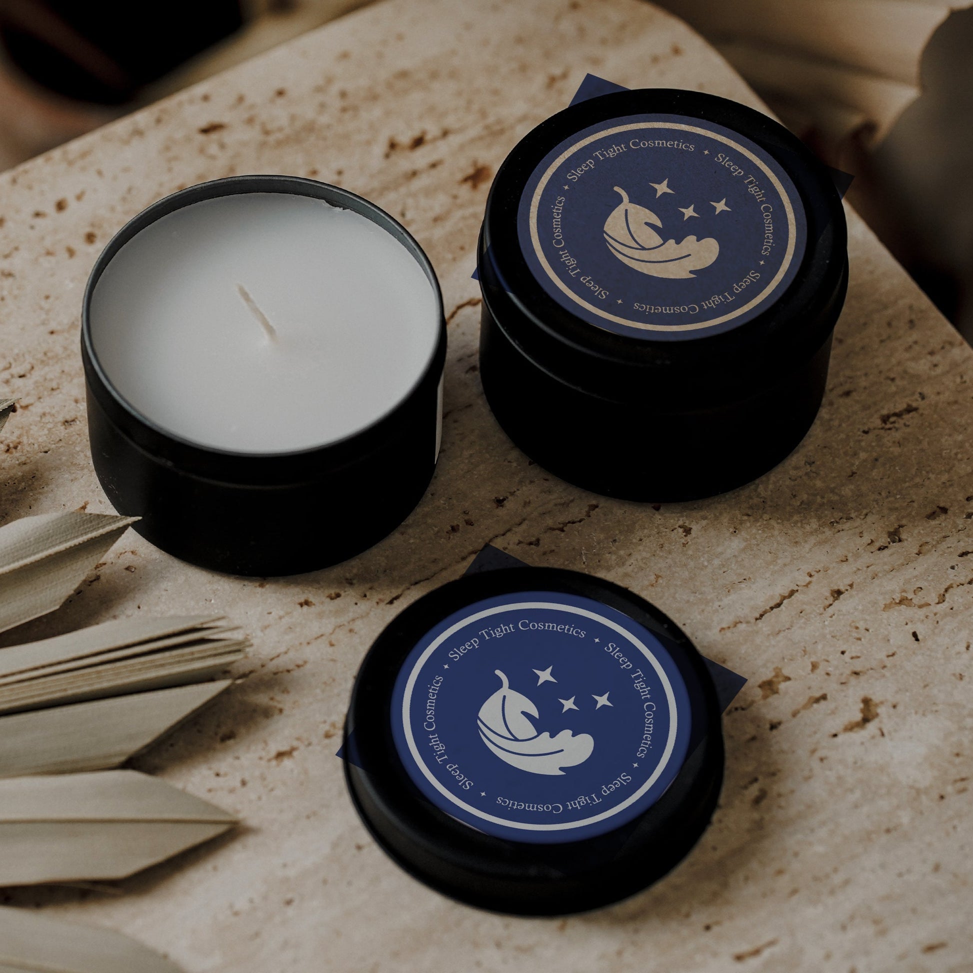 Three black candles with blue labels on a textured surface.