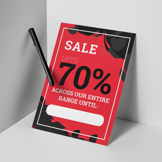 Red and black sale sign with a pen on a white surface
