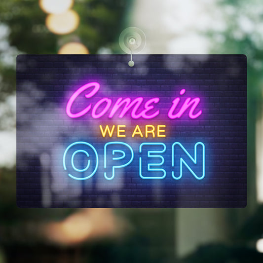 Foam sign with 'Come in, We Are Open' text on a blurred outdoor background